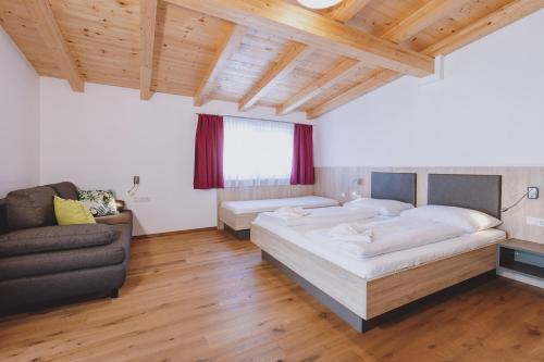a bedroom with two beds and a couch in it at Appartements Sulzer by we rent, SUMMERCARD INCLUDED in Zell am See