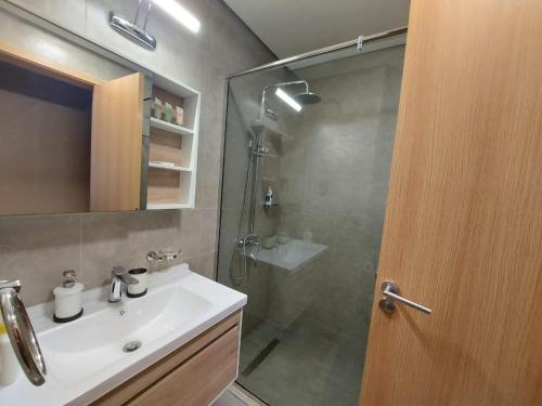 a bathroom with a sink and a shower with a glass door at 1BR Luxury Apartment Pantheon Elysee 1 - JVC in Dubai