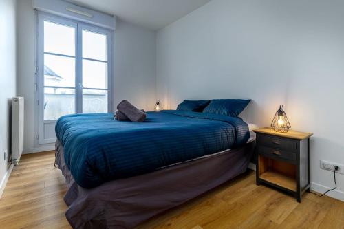 sypialnia z łóżkiem z niebieskim kocem i oknem w obiekcie Appart'Hôtel Gibraltar Disneyland Paris w mieście Serris