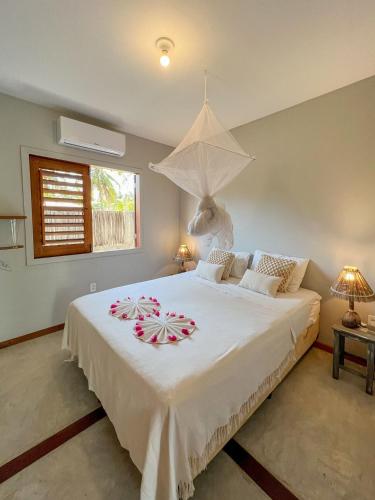 a bedroom with a large white bed with red and white pillows at Casa super charmosa com piscina em Icaraizinho! in Icaraí