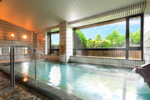 una piscina in un edificio con una grande finestra di たまご肌美人の湯　美榛苑 a Uda