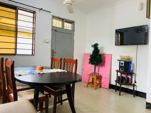 a dining room with a table and a tv at Mikocheni Home stay in Dar es Salaam
