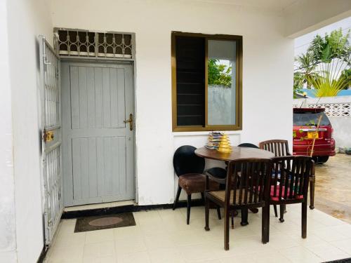 ダル・エス・サラームにあるMikocheni Home stayのテーブルと椅子、ドアが備わる部屋