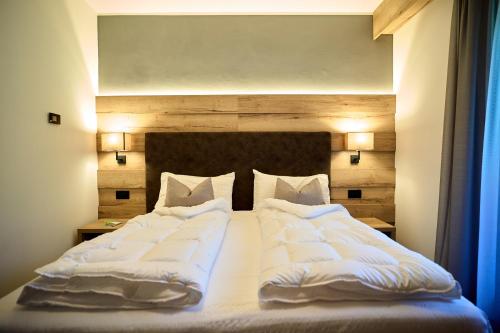 a large bed with white sheets and pillows at Hotel Rio in Caderzone