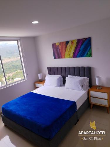 a bedroom with a large bed with a blue blanket at Apartahotel San Gil Plaza in San Gil