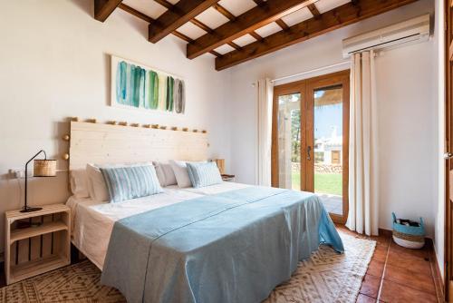 a white bedroom with a large bed with blue sheets at Lasaienea 4 bedroom villa, Cala Morell in Cala Morell