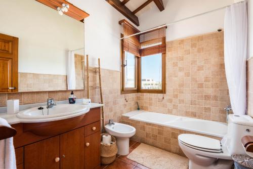 a bathroom with a tub and a sink and a toilet at Lasaienea 4 bedroom villa, Cala Morell in Cala Morell