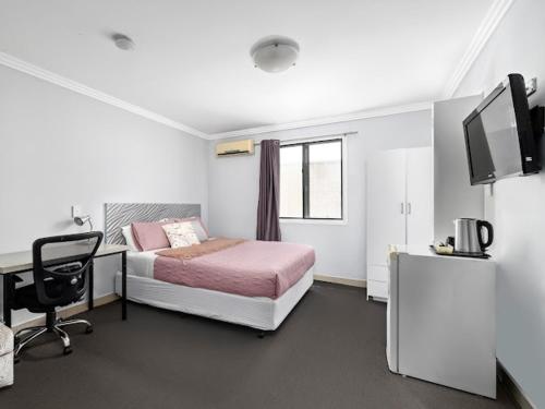 a bedroom with a bed and a desk and a tv at Sunny Rooms Mascot in Sydney