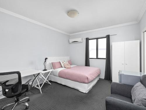 a bedroom with a bed and a desk and a desk at Sunny Rooms Mascot in Sydney
