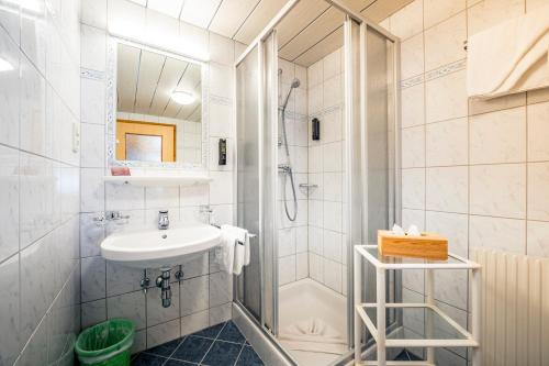 a white bathroom with a sink and a shower at Pension der Steinbock - das 300 Jahre alte Bauernhaus - TIROL in Sankt Anton am Arlberg