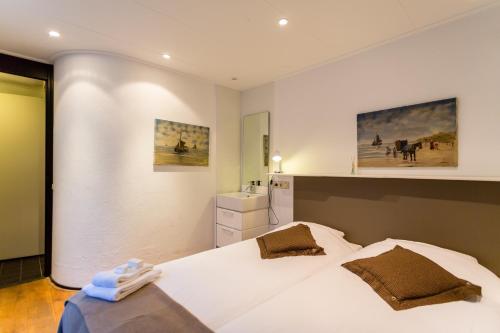 een slaapkamer met een groot wit bed en een wastafel bij Hotel Heerlijkheid Bergen in Bergen