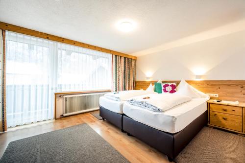 a bedroom with a large bed and a large window at Pension der Steinbock - das 300 Jahre alte Bauernhaus - TIROL in Sankt Anton am Arlberg