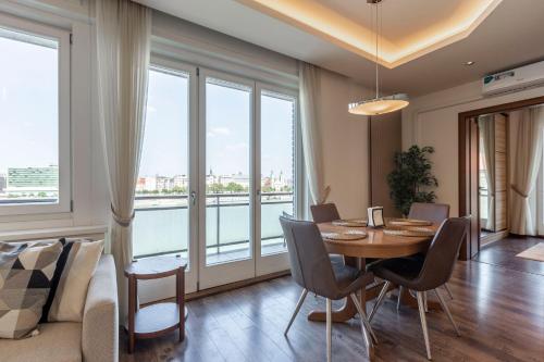 a dining room with a table and chairs and windows at Luxury Residence with a Beautiful view for the Danube River in Budapest