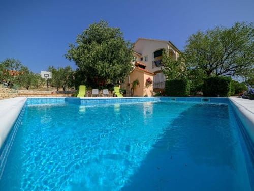 een groot blauw zwembad met een huis op de achtergrond bij Apartman Rokoko in Šibenik