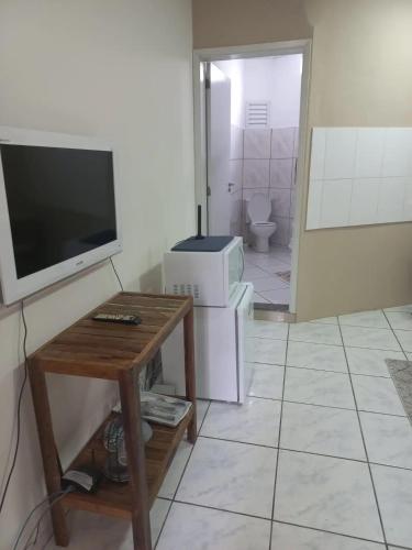uma sala de estar com uma televisão e uma mesa com uma televisão e um micro-ondas em Loft Jardim Botânico 2 em Curitiba