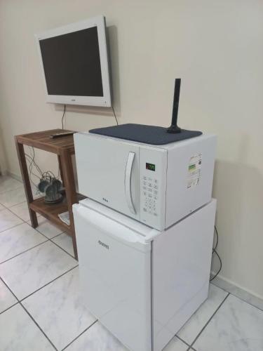 a microwave and a computer sitting on top ofrigerators at Loft Jardim Botânico 2 in Curitiba