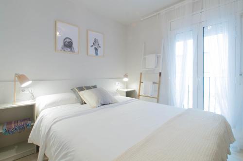 Un dormitorio blanco con una cama blanca y una ventana en Budget Beach Studio 22, en Sant Antoni de Calonge
