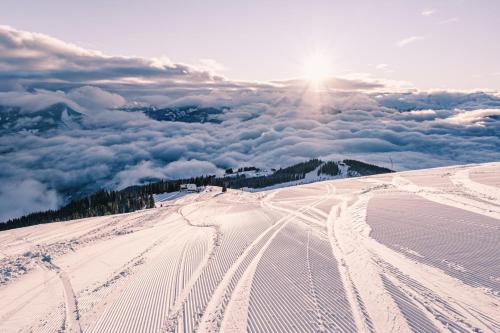 a snow covered slope with the sun in the background at Appartements Sulzer by we rent, SUMMERCARD INCLUDED in Zell am See