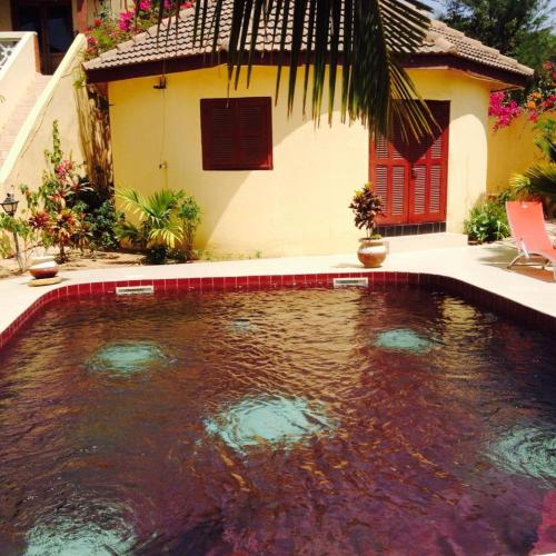 a swimming pool in front of a house at Maison Couleur Passion in Nianing