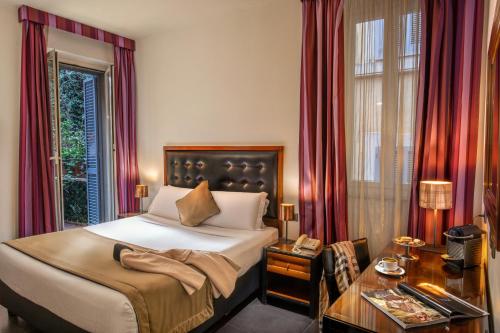 ローマにあるナヴォーナ カラーズ ホテルのベッド、テーブル、窓が備わる客室です。