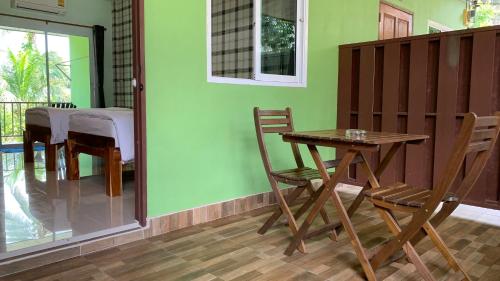 a table and chairs in a room with a table and a dining room at Naisang Hostel in Chumphon