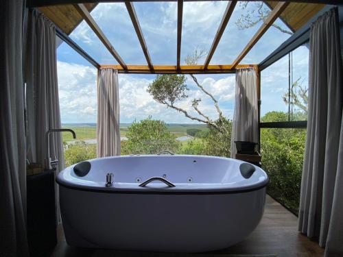uma banheira num quarto com uma grande janela em Morada Alto Das Nuvens em São José dos Ausentes