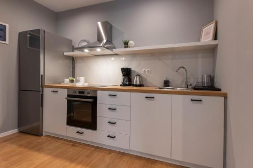 uma cozinha com armários brancos e um frigorífico de aço inoxidável em Athenian center apartments em Atenas