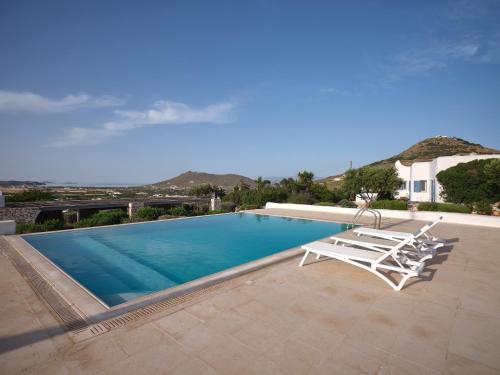 una piscina con due sedie a sdraio e una piscina di Nola Traditional Villa with pool and amazing sea views, Paros a Kampos Paros