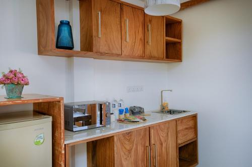 a kitchen with wooden cabinets and a microwave at O2 Villas Yala in Yala