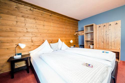 a bedroom with a large bed with a wooden wall at Pension der Steinbock - das 300 Jahre alte Bauernhaus - TIROL in Sankt Anton am Arlberg