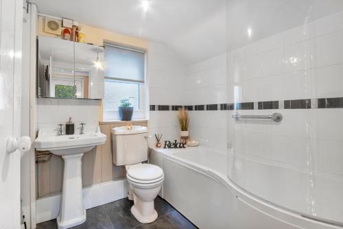 a bathroom with a toilet and a tub and a sink at Rock Cottage in Llanfyllin
