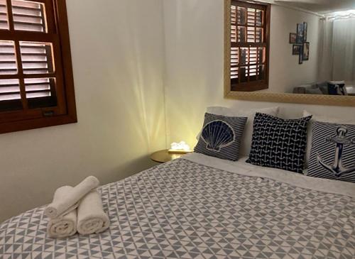 a bedroom with a bed with blue and white sheets and pillows at Loft a 600 metros da praia c piscina em Buzios RJ in Búzios