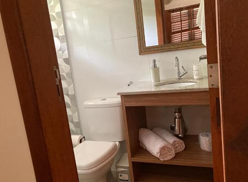 uma casa de banho com um WC, um lavatório e um espelho. em Loft a 600 metros da praia c piscina em Buzios RJ em Búzios