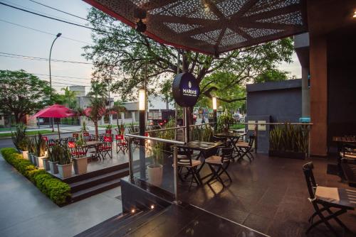 un patio al aire libre con mesas, sillas y plantas en Maria's Hotel en La Banda