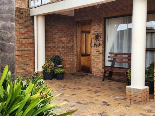 a porch with a wooden door and a wooden chair at Little Greece in Cape Town