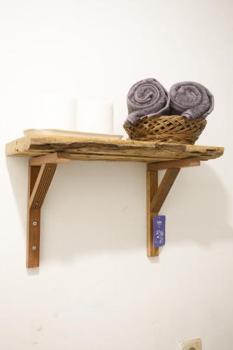 a wooden shelf on a wall with a basket of towels at Rumah Kalpataru in Yogyakarta