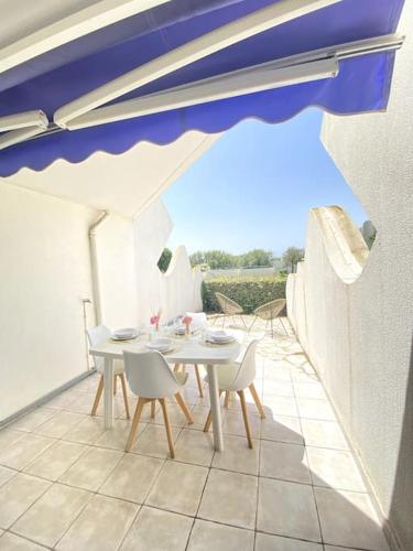 - une table et des chaises sur une terrasse avec un parasol dans l'établissement PGH N17 - Accès Plage à 20m avec Parking Privé, à La Grande Motte