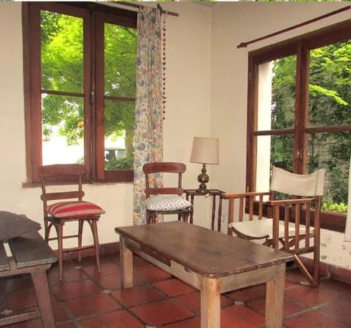 sala de estar con sillas, mesa y ventanas en Amplia casa con parque y pileta en Olavarría