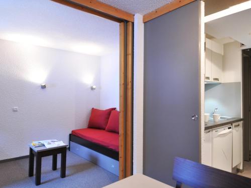 Cette petite chambre comprend un canapé rouge et une table. dans l'établissement Studio Rénové 3/4 Pers, Pied des Pistes, Balcon, La Plagne - FR-1-181-2434, à La Plagne Tarentaise