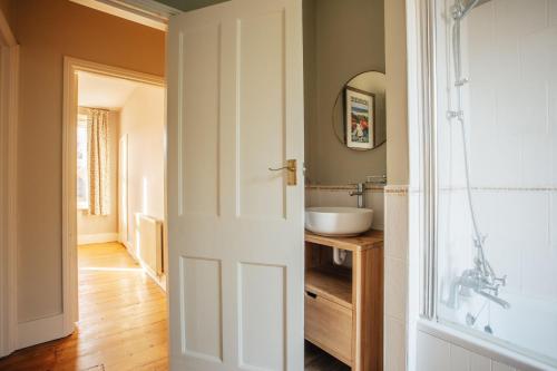 a bathroom with a sink and a white door at Bell Cottage in Alfriston