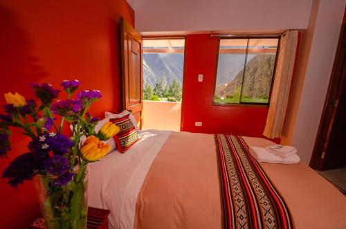a bedroom with a bed with a vase of flowers at Peru Quechua's Lodge Ollantaytambo in Ollantaytambo