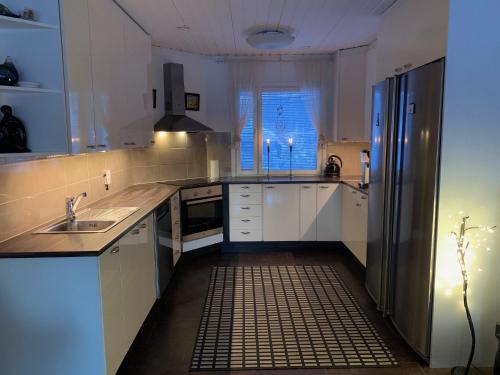 a kitchen with white cabinets and a sink and a window at Riverside Home near Santa Claus Village - beautiful house in a prime location in Rovaniemi