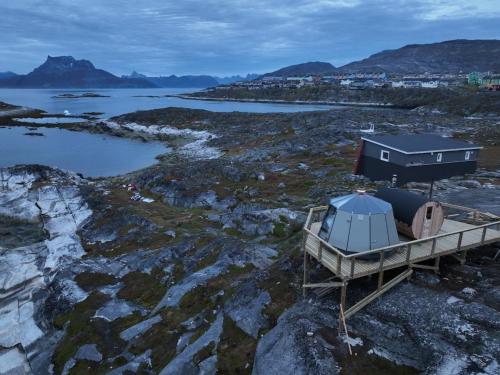 una casa y un barco en una orilla rocosa en Aurora Hut by InukTravel en Nuuk