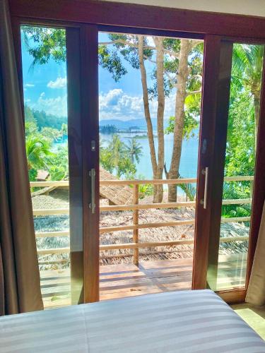 a bedroom with a view of the ocean from a window at Kalulushi Bungalows in Haad Pleayleam