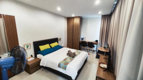 a bedroom with a bed and a desk with a fan at Comfy Studio Kuching in Kuching