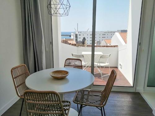 a table and chairs in a room with a balcony at Ladeira Loft - Sea View in the City Center in Ponta Delgada