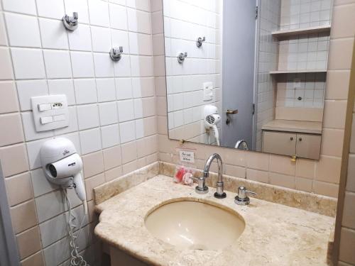 W łazience znajduje się umywalka i lustro. w obiekcie Flat INCRIVEL na Vila Olimpia w São Paulo