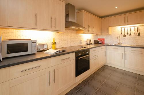 a kitchen with white cabinets and a microwave at The Stables, Elterwater in Elterwater