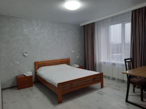 a bedroom with a bed and a table and a window at PerfectHotel in Myrhorod