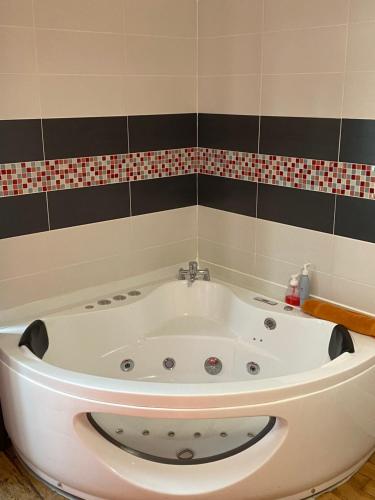 a white bath tub in a bathroom with a tile wall at Chambres d'Hôtes Au coin du spa in Boulogne-sur-Mer